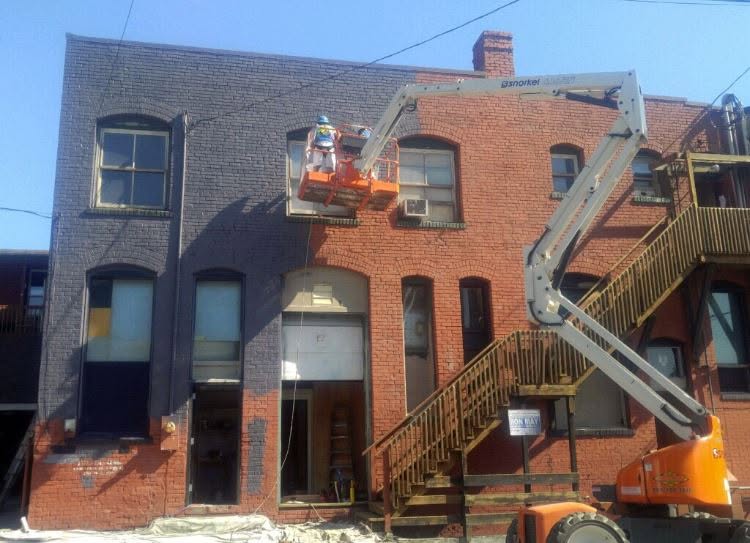 Commercial Building Exterior Painting - Remington Services Crew painting the exterior of a multi-story commercial brick building using a boom lift in Western Washington..